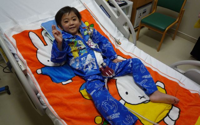 拡張型心筋症と診断され、入院していた由宇人さん。子ども用の補助人工心臓をつけているので、血液を循環させるポンプが見えています＝父・慎也さん提供