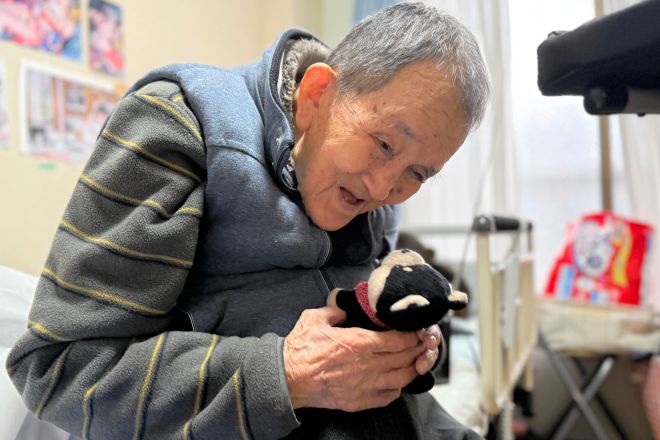 声を再生してくれるぬいぐるみ「ごんた」がお気に入り。「ごんた、お客さんや」と声をかけ、再生した声を記者に聞かせてくれた=2025年12月4日、北九州市八幡東区、山下知子撮影